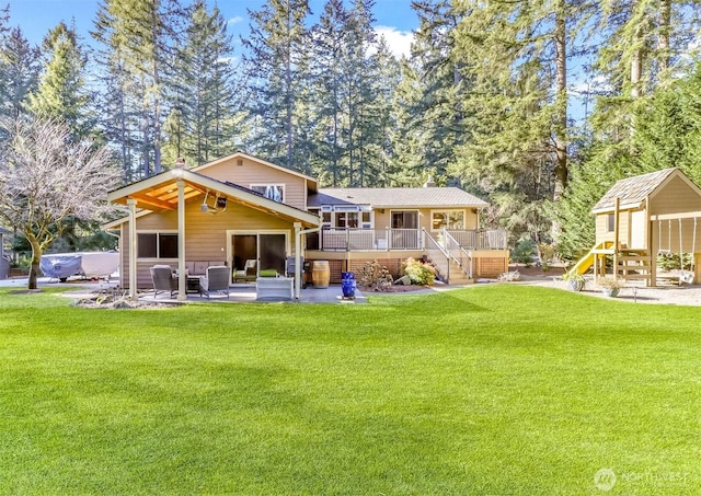 rear view of house with a playground, a patio, a lawn, and a wooden deck