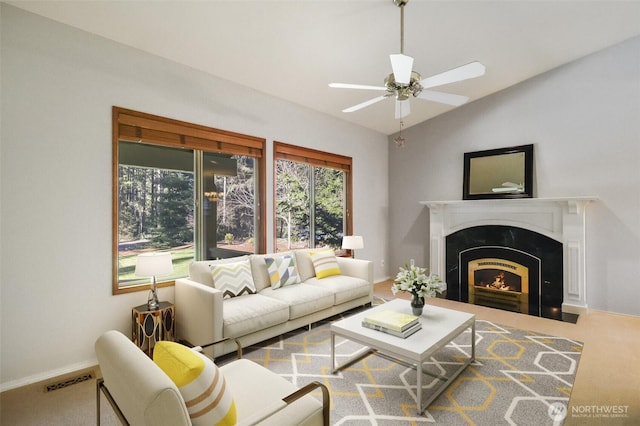 living room with ceiling fan, lofted ceiling, a premium fireplace, and carpet