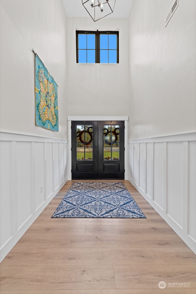 foyer with an inviting chandelier, light hardwood / wood-style floors, and french doors