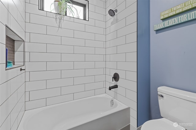 bathroom featuring tiled shower / bath combo and toilet