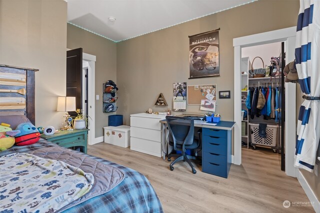 bedroom with a spacious closet, a closet, and light wood-type flooring