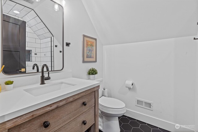 bathroom featuring vanity, toilet, and vaulted ceiling