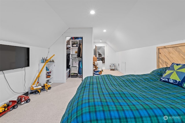 bedroom with light carpet, a spacious closet, vaulted ceiling, and a closet