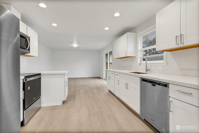 kitchen featuring stainless steel appliances, sink, white cabinets, and light wood-type flooring