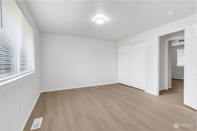 unfurnished bedroom with light hardwood / wood-style flooring and a closet