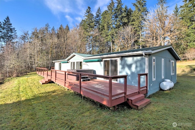 rear view of house featuring a wooden deck, a lawn, and a hot tub