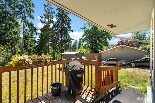 deck featuring a storage shed and a grill