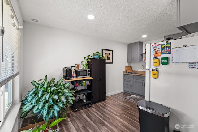 kitchen with gray cabinetry, dark hardwood / wood-style flooring, a textured ceiling, and white fridge