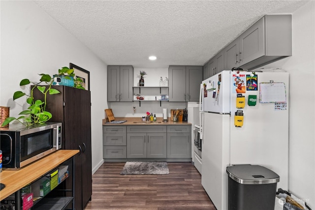 kitchen featuring sink, gray cabinetry, dark hardwood / wood-style floors, white refrigerator, and a textured ceiling