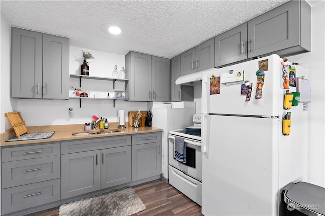 kitchen featuring sink, gray cabinetry, a textured ceiling, dark hardwood / wood-style flooring, and white appliances