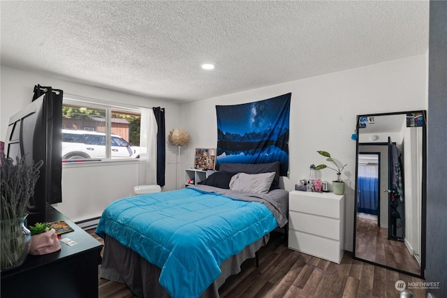 bedroom with baseboard heating, dark hardwood / wood-style floors, and a textured ceiling