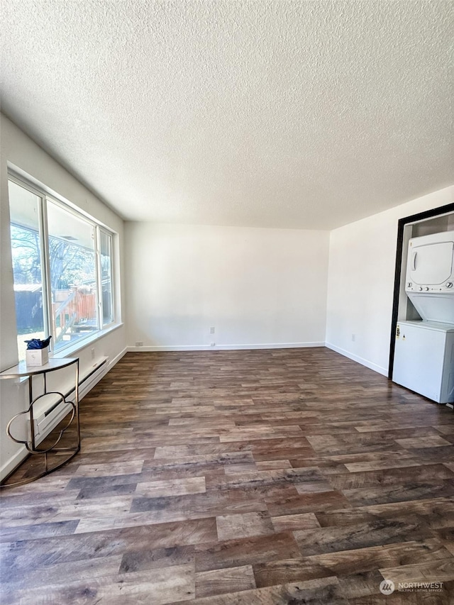 empty room featuring dark wood-type flooring, stacked washer / dryer, and a textured ceiling