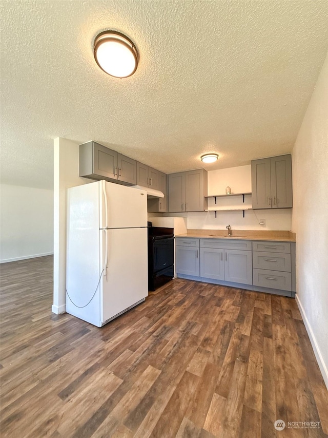 kitchen featuring gray cabinetry, range, a textured ceiling, dark hardwood / wood-style flooring, and white fridge