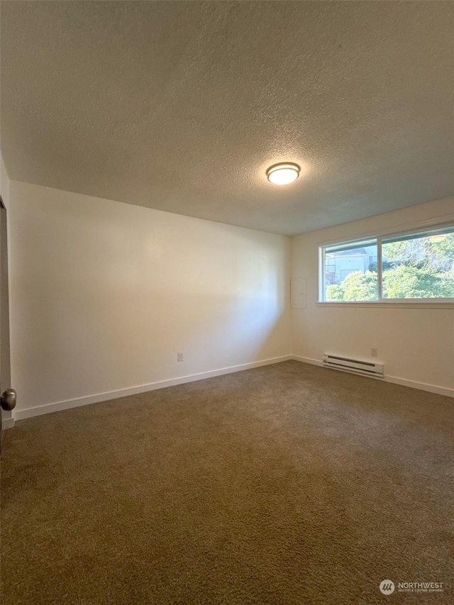 empty room with a baseboard heating unit, a textured ceiling, and dark carpet