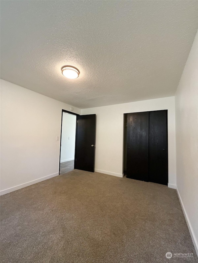 unfurnished bedroom featuring carpet floors, a closet, and a textured ceiling