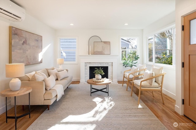 sitting room featuring a brick fireplace, a wall mounted AC, and light hardwood / wood-style floors