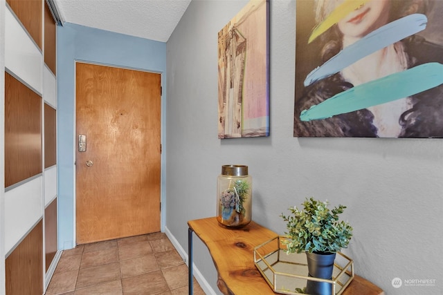 entryway featuring baseboards, a textured ceiling, and tile patterned floors