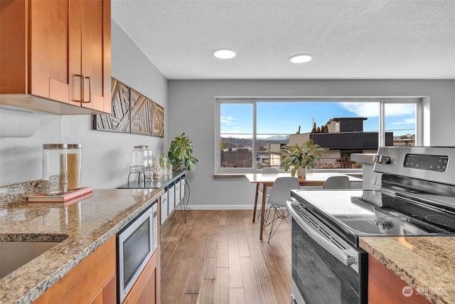 kitchen featuring brown cabinetry, light wood-style flooring, and stainless steel appliances