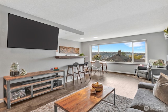 living area with a textured ceiling, baseboards, and wood finished floors