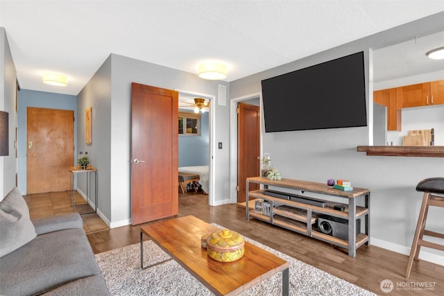 living room with ceiling fan, baseboards, and wood finished floors