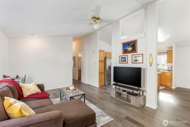 living area featuring lofted ceiling, ceiling fan, baseboards, and wood finished floors