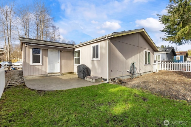 rear view of property featuring a lawn, a patio area, and fence