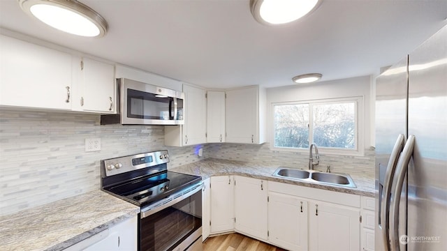 kitchen featuring stainless steel appliances, white cabinetry, sink, and decorative backsplash