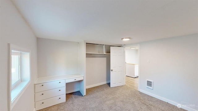 unfurnished bedroom featuring light carpet and a closet