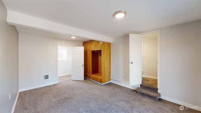 unfurnished bedroom featuring ensuite bath, carpet, and a closet