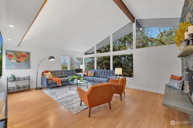 living room with beamed ceiling, a stone fireplace, high vaulted ceiling, and light hardwood / wood-style floors