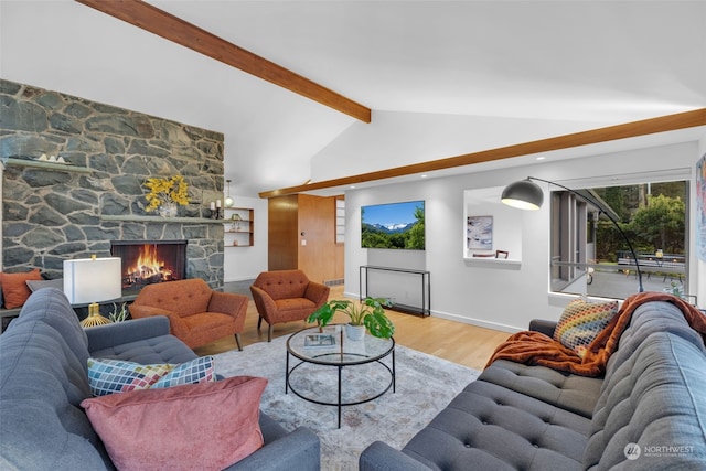 living room featuring hardwood / wood-style flooring, a stone fireplace, and lofted ceiling with beams