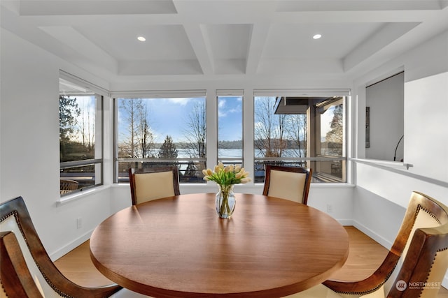 dining space featuring beamed ceiling, coffered ceiling, and light hardwood / wood-style flooring