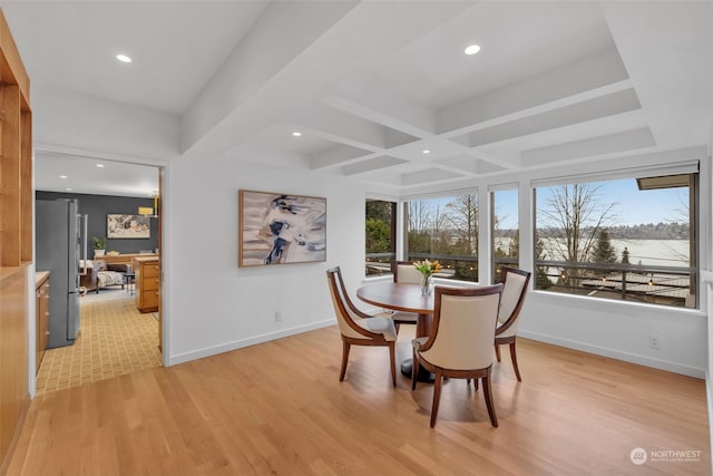 dining area featuring beamed ceiling, plenty of natural light, coffered ceiling, and light hardwood / wood-style floors