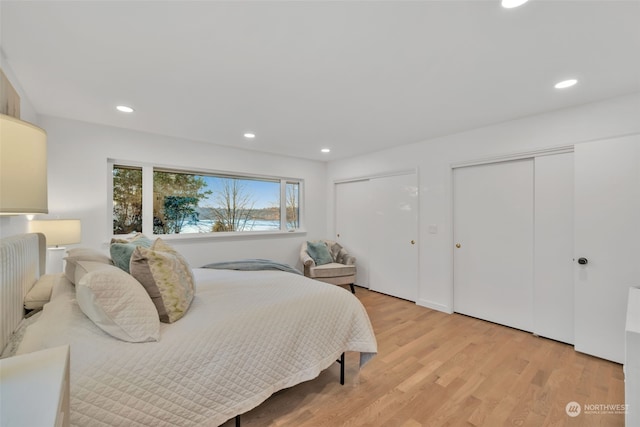 bedroom featuring light hardwood / wood-style flooring and multiple closets