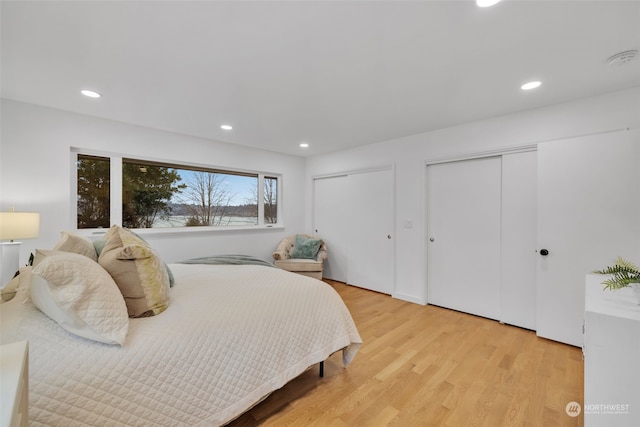 bedroom with two closets and light hardwood / wood-style flooring