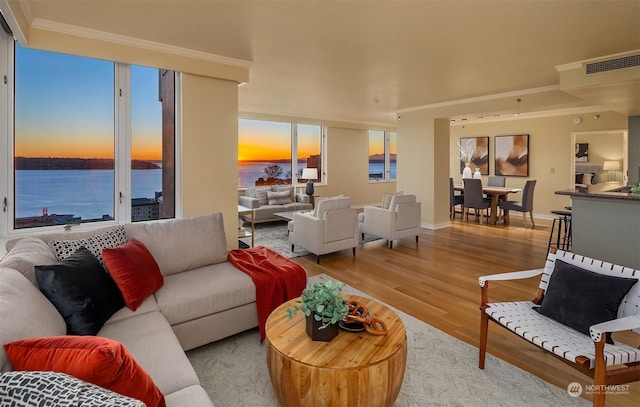 living room featuring a water view, ornamental molding, light hardwood / wood-style floors, and plenty of natural light