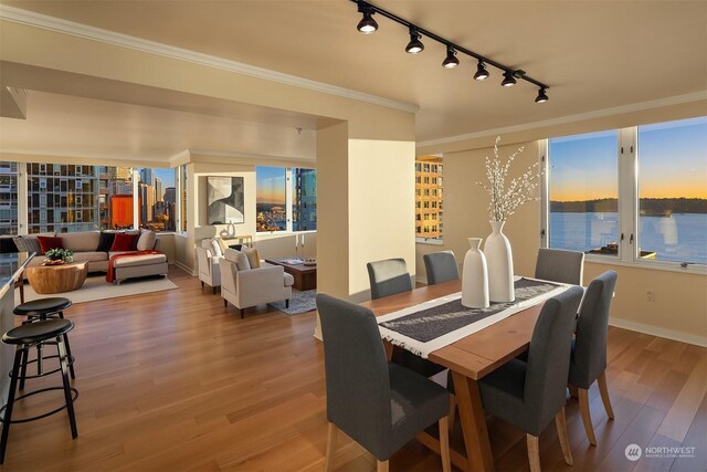 dining room with ornamental molding, a water view, and hardwood / wood-style floors