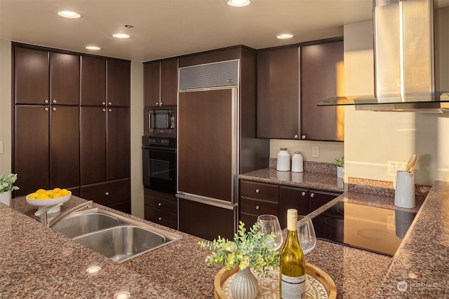 kitchen with wall chimney range hood, sink, dark brown cabinetry, black appliances, and dark stone counters