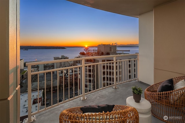 balcony at dusk featuring a water view