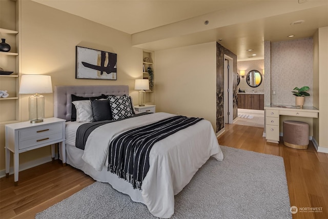 bedroom with ensuite bath and light wood-type flooring