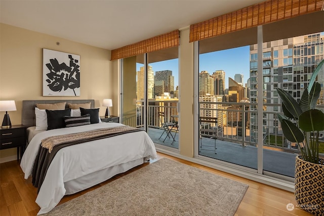 bedroom featuring access to exterior, hardwood / wood-style flooring, and floor to ceiling windows