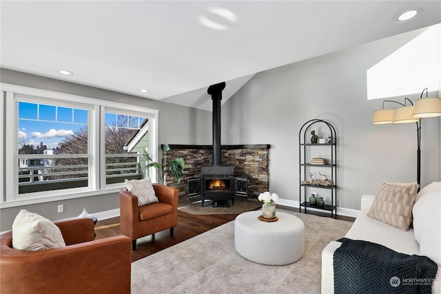 living room with lofted ceiling, a wood stove, and hardwood / wood-style floors