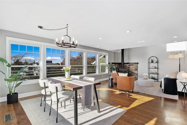 dining room featuring hardwood / wood-style floors, a chandelier, and a wood stove