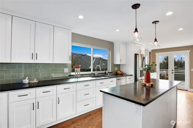 kitchen with sink, white cabinetry, decorative light fixtures, a kitchen island, and stainless steel appliances