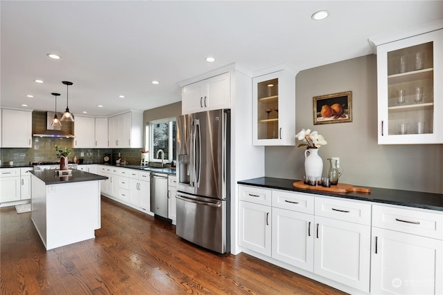 kitchen featuring a kitchen island, decorative light fixtures, sink, stainless steel appliances, and wall chimney exhaust hood