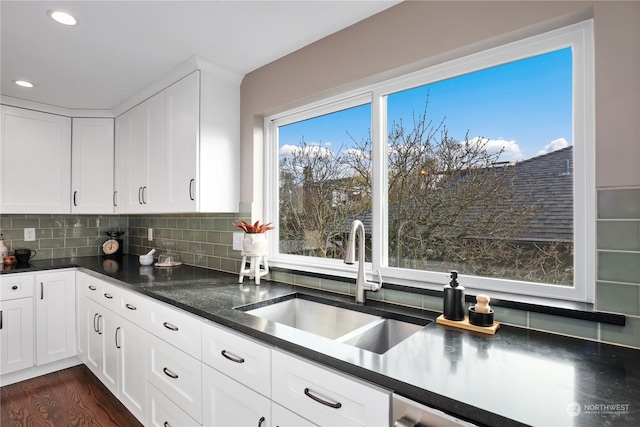 kitchen with tasteful backsplash, sink, dark wood-type flooring, and white cabinets