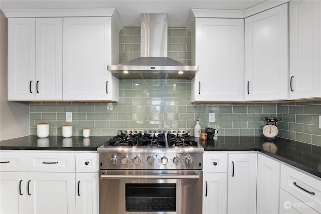 kitchen with white cabinetry, tasteful backsplash, high end stainless steel range oven, dark stone counters, and wall chimney range hood