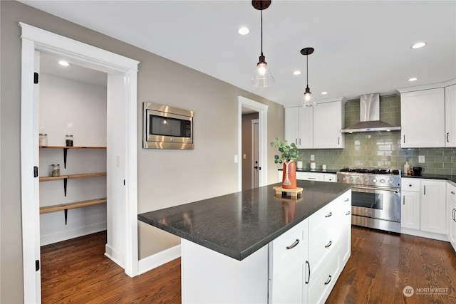 kitchen with wall chimney exhaust hood, a center island, appliances with stainless steel finishes, white cabinets, and backsplash