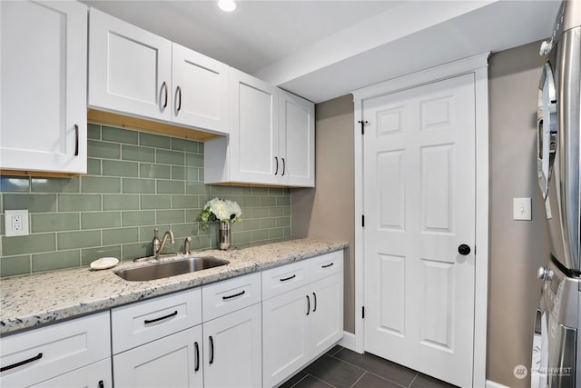 kitchen with light stone counters, sink, and white cabinets