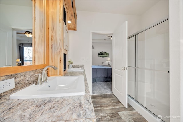 bathroom with sink, a shower with shower door, hardwood / wood-style floors, and ceiling fan